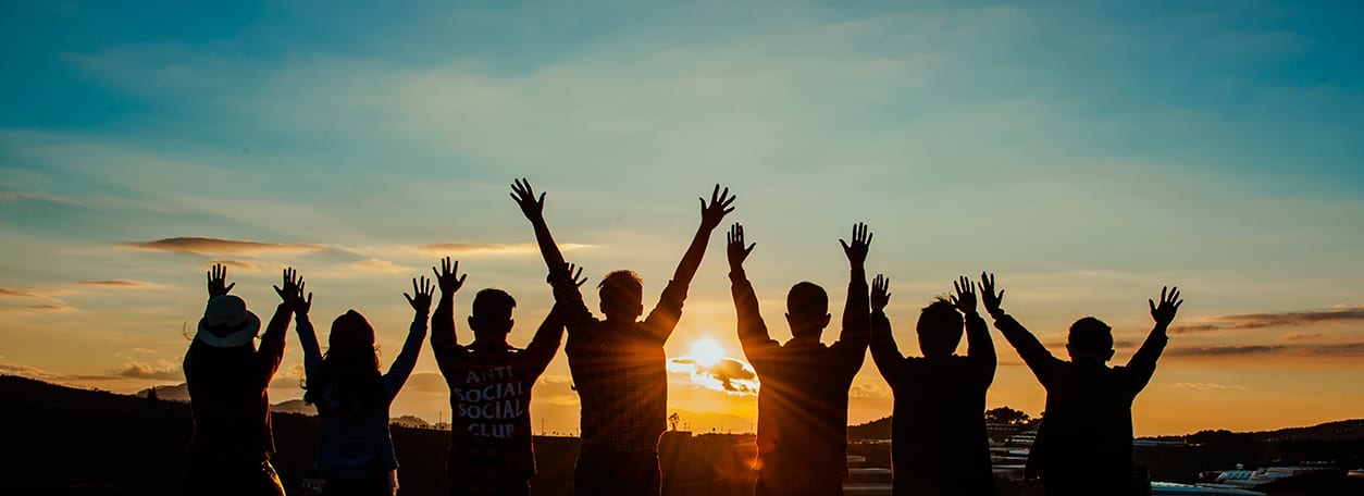 people cheering at sunset